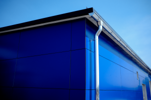 Blaue Aluverbund Fassade mit Fallrohr und Dachrinne