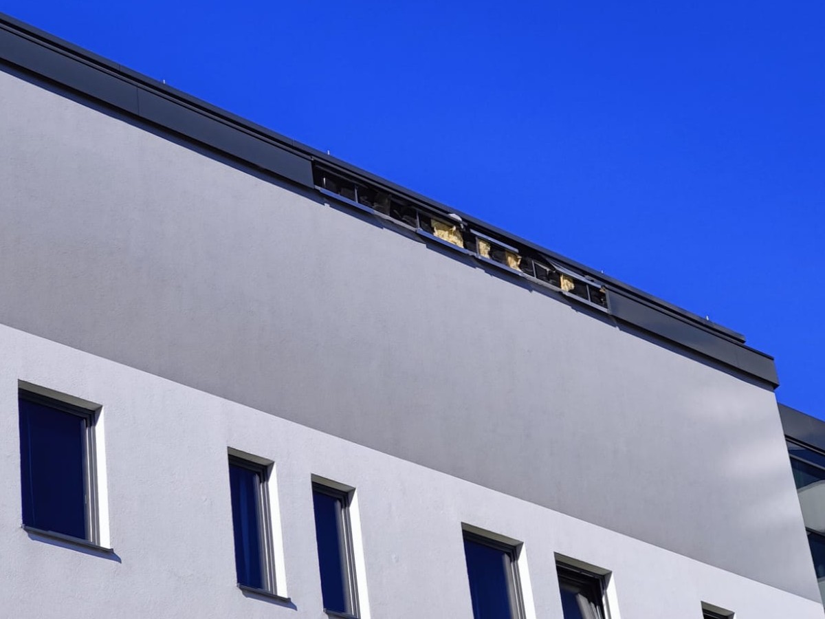 Sturmschaden am Dachrand einer Fassade mit freiliegender Dämmung und beschädigter Attikaverkleidung
