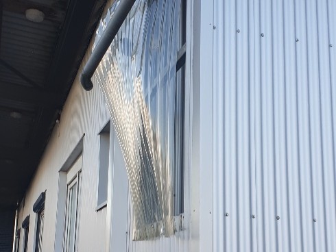 Sturmschaden an Fassadenverkleidung mit herausgerissenem Lichtbauelement